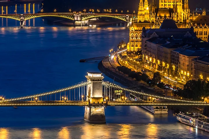 The Chain Bridge lit up at night over the Danube in Budapest, with the river reflecting the lights